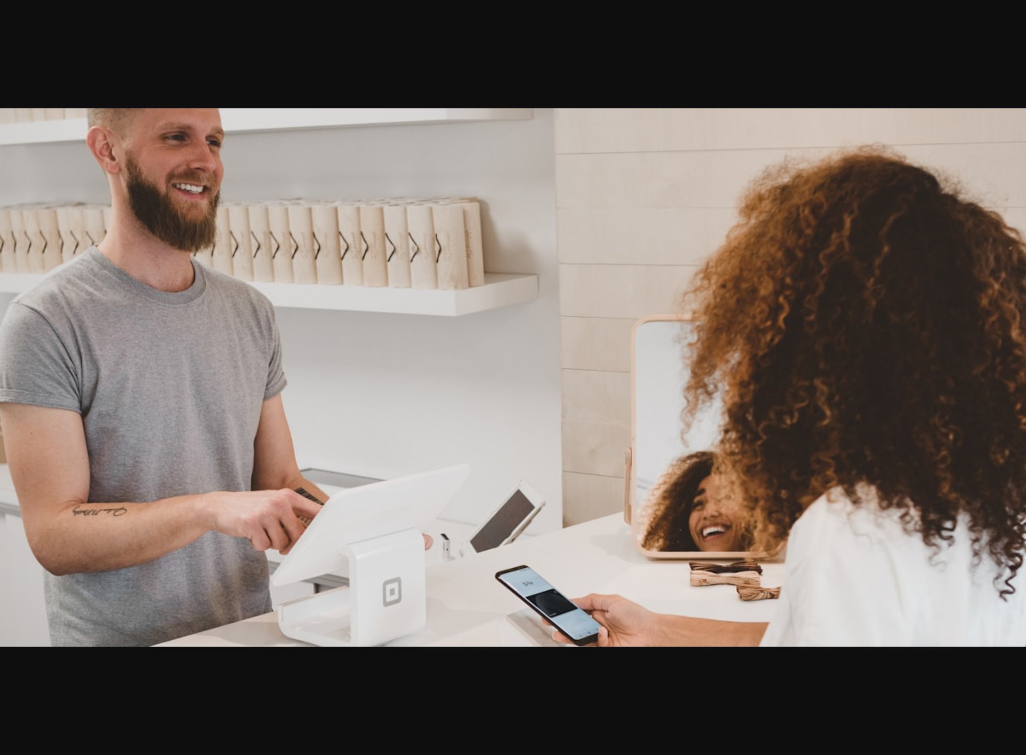 Seseorang berbelanja online menggunakan smartphone di depan laptop